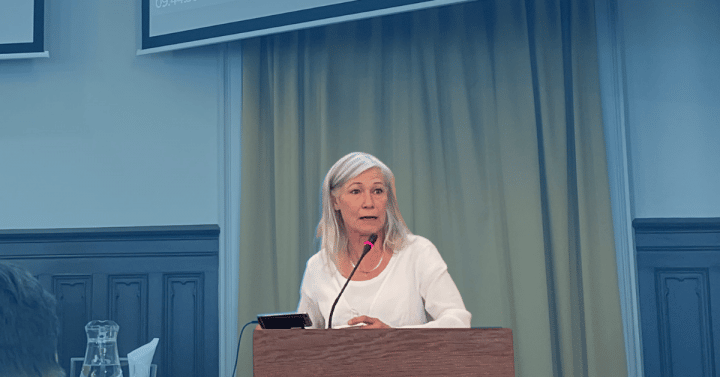 Bild på Karolina Wallström i talarstol med blå bakgrund
